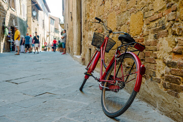 San Quirico d'Orcia, Tuscany: Red bicycle leaning against an old wall along the street - 640783734