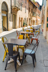San Quirico D'Orcia, Tuscany - August 2023: chairs and tables of a bar on a street in the historic centre.