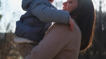 Happy family outdoor. Mother embracing her child outdoor. Mom lifting in air little toddler child son. Woman and little baby boy resting walking in park. Mother hugs baby with love care