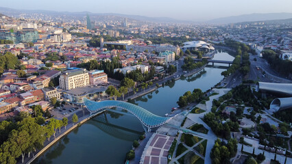 Sunrise in  Georgian capital -Tbilisi , pedstrian bridge of  Peace over Kura river and  cityscape...
