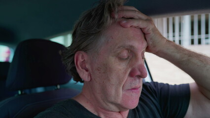 Preoccupied senior man in distress struggles with depression and solitude inside car. Overwhelmed...