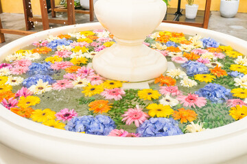 Mixed colorful flowers floating in water in classic style fountain.