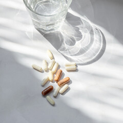 Minimal beauty, wellness, pharmaceutical industry concept. Different pills, capsules, glass with...