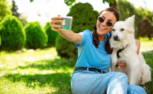 Close up photo of young smiling girl takes selfie with her white Dog outdoor on the lawn. Adoption, rescued, shelter, companion, pet, best friend.