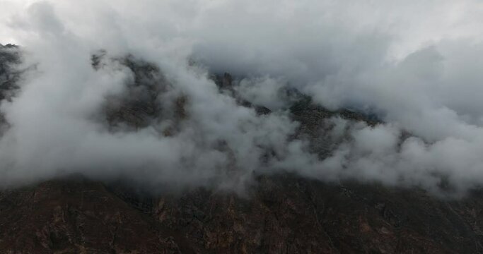 Aerial View of mountains covered in mystical clouds, drone orbits around them. A spectacle in the serene Hunza Valley,of Gilgit Baltistan, Pakistan.