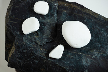 four white smooth stones laying over one black flat stone surface