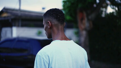Fototapeta premium One pensive black man walking forward in street in deep mental reflection and worried emotion. Tracking motion shot of a Brazilian person strolling in urban setting