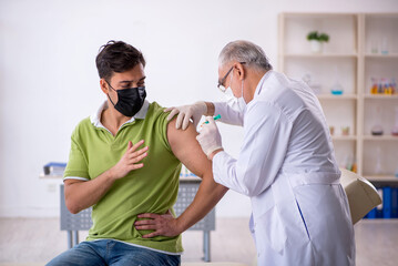 Young male patient visiting old male doctor in vaccination conce