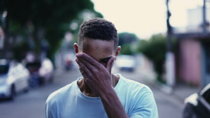 One pensive black man walking forward in street in deep mental reflection and worried emotion....