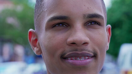One Happy Black Young Man gazing upwards at sky smiling with HOPE and FAITH. Close-up face of a...