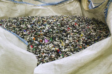 Shredded plastic pieces prepare for recycling. Raw cables material for reproduction. Sorting garbage on waste plant. Pile of scrap bottles on trash storage factory. Environmental concept