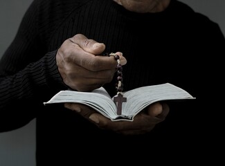 man praying to god with hands on bible together with black grey background stock image stock photo	