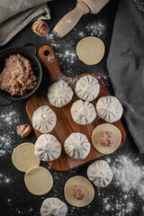 Traditional frozen homemade  georgian khinkali or manty dumplings. Ravioli set on a wooden cutting board on a dark table, top view flat lay