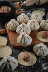Traditional frozen homemade  georgian khinkali or manty dumplings. Ravioli set on a wooden cutting board on a dark table