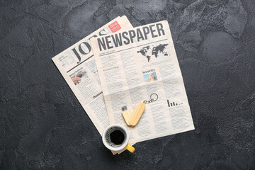 Newspapers with USB flash drive and cup of coffee on dark background