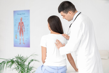 Obraz premium Male doctor checking posture of young woman in clinic