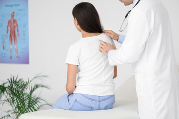 Male doctor checking posture of young woman in clinic