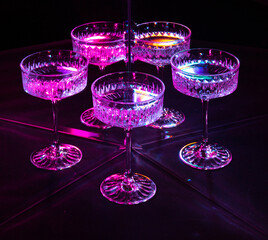 A glass of wine reflected in mirrors and illuminated by colored light
