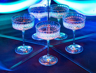 A glass of wine reflected in mirrors and illuminated by colored light