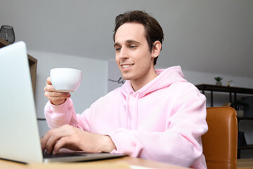 Male freelancer with cup of coffee working at table in office