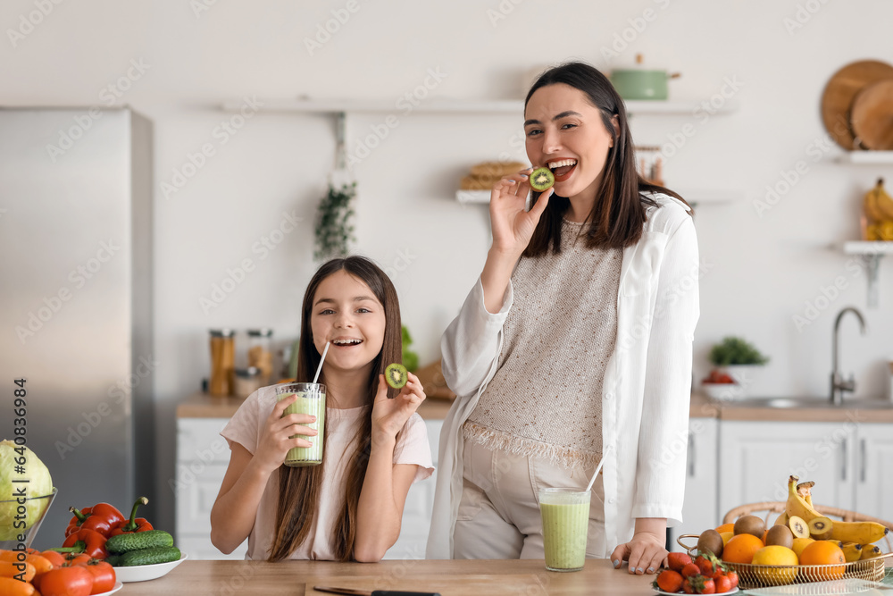 Canvas Prints Little girl with her pregnant mother drinking green smoothie in kitchen