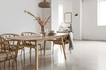 Interior of stylish dining room with blooming sakura branches on table