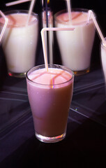 glasses with a milkshake reflected in mirrors and illuminated by colored light