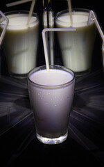 glasses with a milkshake reflected in mirrors and illuminated by colored light