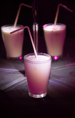 glasses with a milkshake reflected in mirrors and illuminated by colored light