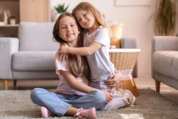 Cute little sisters hugging at home