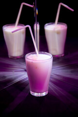 glasses with a milkshake reflected in mirrors and illuminated by colored light