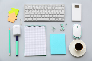 Composition with stationery, gadgets and cup of coffee on grey background