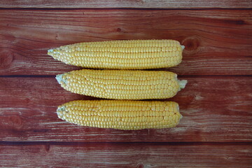 Cobs of fresh raw corn on wooden background