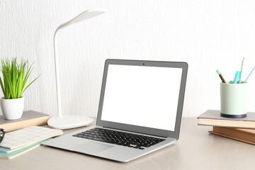 Fototapeta premium Comfortable workplace with modern laptop, books and houseplant on beige table