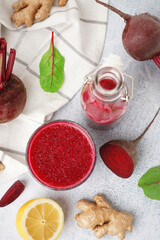 Bottle and glass of fresh beetroot juice with ingredients on light background