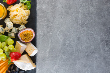 Various types of cheese with fruits and sauces. Empty space background concept