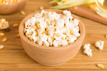 Prepared popcorn with ingredients on wooden table