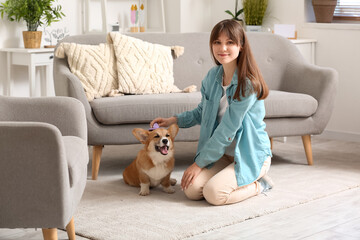 Pretty young woman with cute Corgi dog on floor in living room