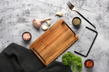 Composition with wooden kitchen board and different spices on grunge background