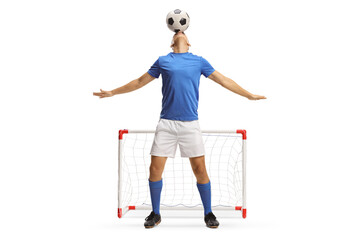 Football player holding a ball with head in front of a mini goal
