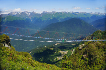 woman rouring walking on rope suspension bridge in caucasus mountains, Russia, Rosa Khutor resort