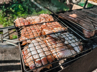 Close-up of cooking meat on the grill on the grate on a clear sunny day