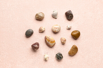 Fototapeta na wymiar Many pebble stones and seashells on pink background