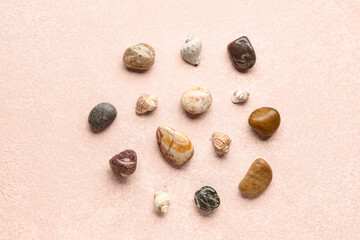 Many pebble stones and seashells on pink background