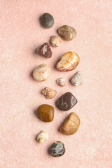 Many pebble stones and seashells on pink background