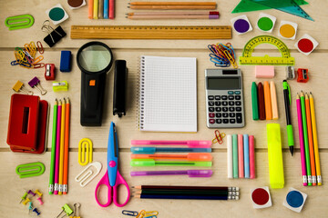 Colorful school supplies designed on wooden table, with blank checkered notebook,Conceptual image of education