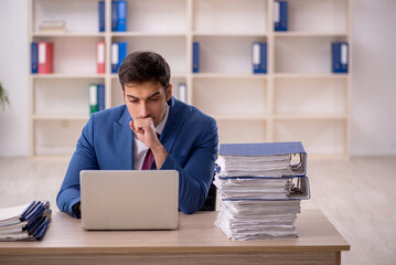 Obraz premium Young male employee and too much work in the office