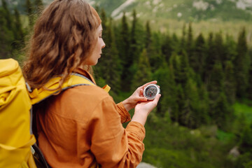 
Wanderlust concept. Stylish woman holding a compass in her hand while traveling in the mountains....