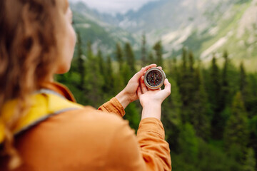 
Wanderlust concept. Stylish woman holding a compass in her hand while traveling in the mountains....