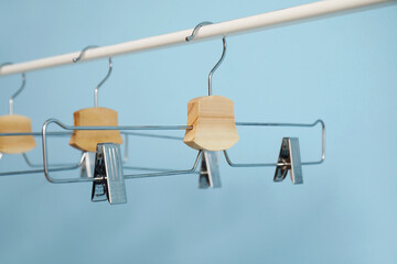 Rack with metal clothes hangers on blue background